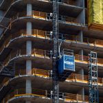 Detailed view of a high-rise building construction featuring a crane and multi-level scaffolding.