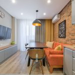 Stylish apartment interior with a brick wall, orange sofa, and wooden furniture.